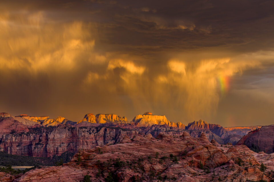 Dramatic storm clouds illuminate red rock formations during monsoon season in Zion National Park at sunset