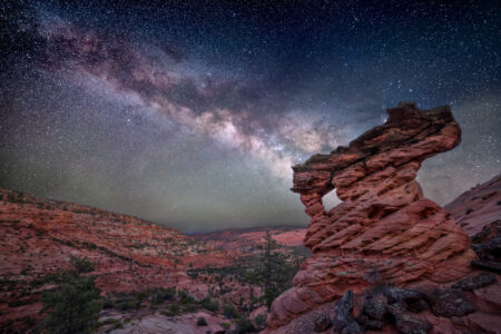 Twisted sandstone formation in Zion National Park beneath the Milky Way glowing across a clear night sky.