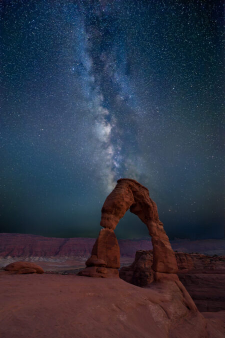 A clear night sky at Delicate Arch in Arches National Park. The Milky Way rises straight up over the arch.