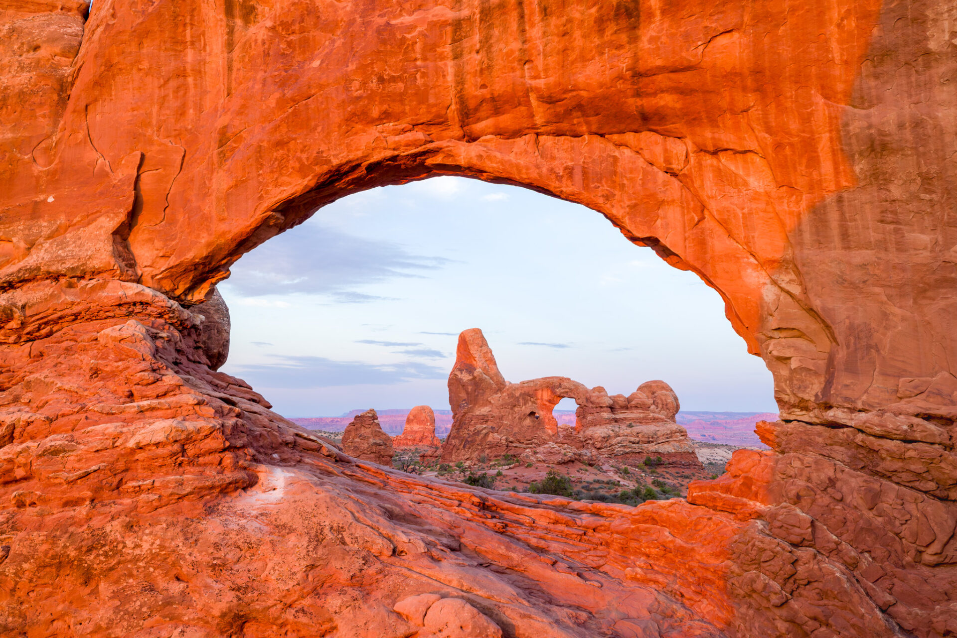 A view of Turret Arch in Arches National Park looking through the North Window. Warm Sunrise light bathes the sandstone.